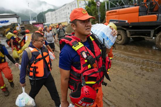 Firefighters trek uphill to aid stranded residents in Beijing after heavy rains