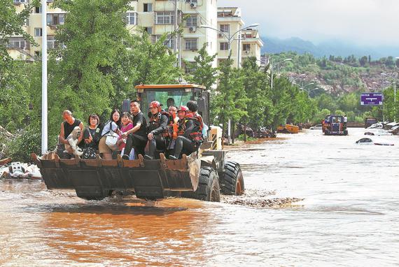 Rescuers use a bulldozer to evacuate residents trapped by floodwaters in Taishitun township in Beijing's Miyun district on Monday. (CHEN JIAN/FOR CHINA DAILY)