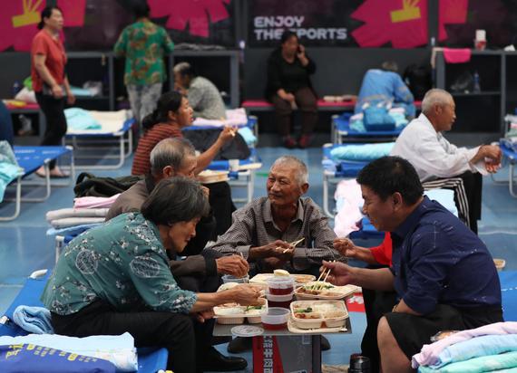 Residents eat on Tuesday at a resettlement site that was set up at the sports center in Beijing's Pinggu district. (CHEN ZEBING / CHINA DAILY)