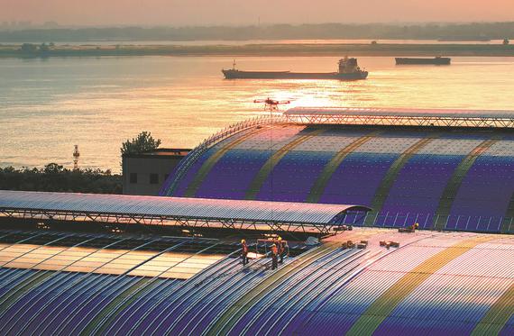 Employees use a drone to maneuver photovoltaic panels for installation on the roof of a coal shed in Ma'anshan, Anhui province, on May 5. ZHANG MINGWEI/FOR CHINA DAILY