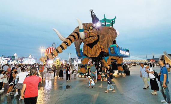 People watch and take pictures of a nine-meter-high and 16-meter-long mechanical elephant during the 23rd Harbin International Beer Festival in Harbin, Heilongjiang province, on Aug 9. (ZHANG SHU/FOR CHINA DAILY)