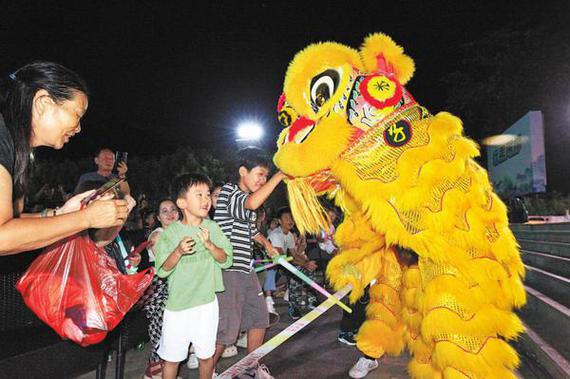 A lion dancer (right) interacts with tourists at a scenic spot in Luoyang, Henan province, on July 30. (NIU SHUPEI/FOR CHINA DAILY)