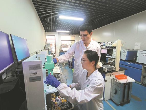 Researcher Deng Peilin (standing) instructs a student on conducting performance tests for the conversion of methane to methanol under mild conditions. （Photo provided to China Daily）