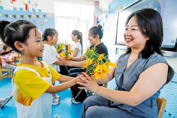 Children present flowers to their teachers at a kindergarten in Zunhua, Hebei province, on Tuesday to celebrate the 41st Teachers' Day in China, which falls on Wednesday.  （Liu Mancang / For China Daily）