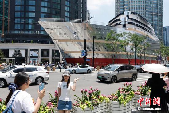 A tourist takes a photo in front of "The Louis," LV's first luggage-shaped store in China, June 27, 2025. (Photo/China News Service)