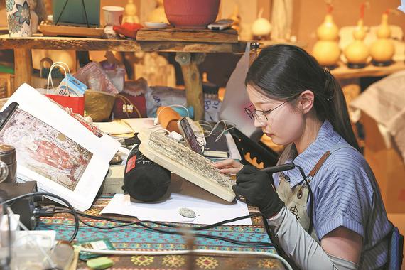 A learner practices pyrography at a studio at Tuyugou Cultural Tourism Town in Shanshan county on Sept 9. (WANG ZIRU/CHINA NEWS SERVICE) A learner practices pyrography at a studio at Tuyugou Cultural Tourism Town in Shanshan county on Sept 9. (WANG ZIRU/CHINA NEWS SERVICE)