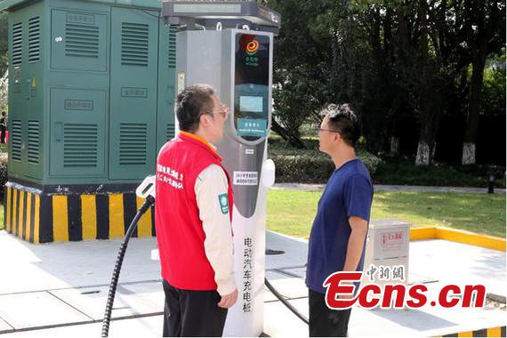 Wang Lihui (left), team leader of the State Grid Shanghai Jinshan Power Supply Company, demonstrates how to use the new charging system to a driver at Fengjing Service Area in Shanghai, Sept. 30, 2025.  (Photo/Jiang Weiwei)