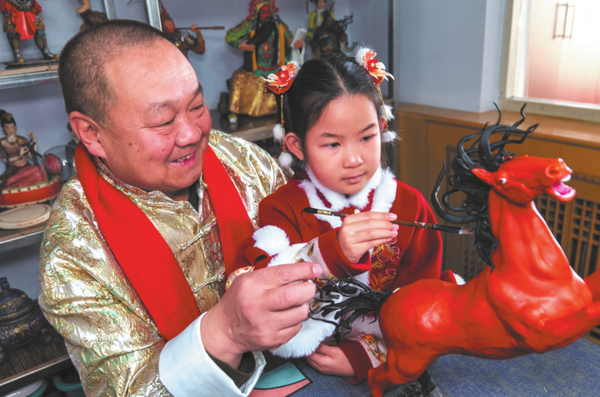 A child paints a dough horse, experiencing traditional artistry hands-on in Xuanhua district, Zhangjiakou. （CHINA DAILY）