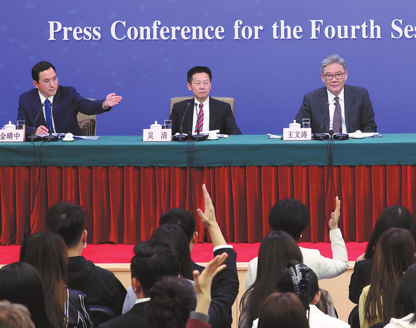 Wu Qing (center), chairman of the China Securities Regulatory Commission, at a news conference on the sidelines of the fourth session of the 14th National People's Congress on Friday. (Wang Jing/China Daily)
