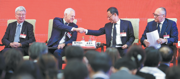 Bill Winters (second from left), group chief executive of Standard Chartered, and Zhang Baojiang (second from right), president of the Bank of Communications, greet each other during a panel discussion of the China Development Forum in Beijing on Monday. Guests at the symposium shared their insights into the role of financial innovation in supporting high-quality development. (China News Service/ Jiang Qiming)