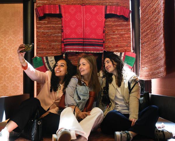 People pose for a selfie with exhibited carpets and clothes at an exhibition inspired by the culture of Hongyao, a branch of the Yao ethnic group, in south China's Guangxi Zhuang Autonomous Region, during Milan Design Week at Plazzo Litta in Milan, Italy, April 23, 2026. (Xinhua/Li Jing)