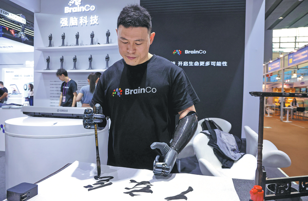 An employee from BrainCo showcases using intelligent bionic hands to practice calligraphy during the 135th China Import and Export Fair in Guangzhou, Guangdong province on April 15, 2024. (LIU DAWEI/XINHUA)