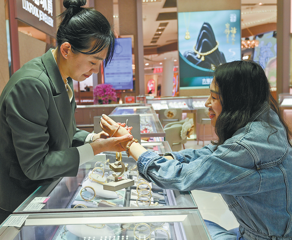 A shopper tries out a golden bracelet at a jewelry store in Qingzhou, Shandong province. （WANG JILIN/FOR CHINA DAILY）