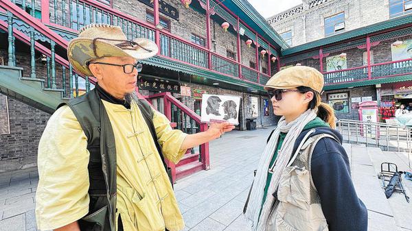 Wang makes a paper-cut silhouette portrait for a customer at his stall. (Zhou Huiying/China Daily)
