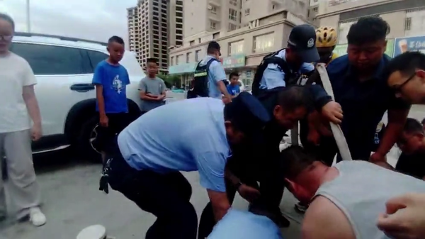 A police officer in Hejing County, Xinjiang,  rescues a 5-year-old boy and his father after the two become trapped in an uncovered sewage well filled with roughly three meters of sewage. (Screenshot from CNS video)