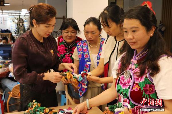 Ding Lanying (far left) exchanges with female embroiderers over embroidery techniques for World Cup-themed orders. (Photo: China News Service/Xie Xiaojia)
