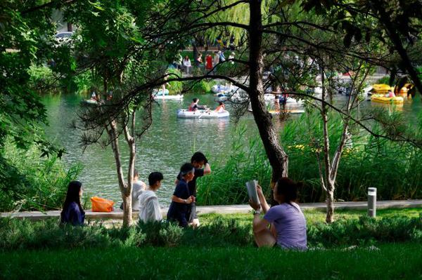 Residents and visitors enjoy boating, swimming and reading along the Liangma River in Beijing on June 21, 2026. (Photo: China News Service/Han Haidan)