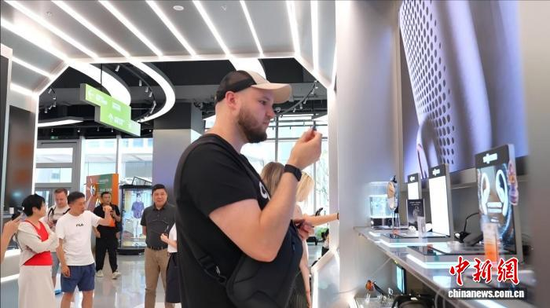 Foreign tourists stop by the intelligent sensing experience zone to try on wearable devices, July 17, 2026. (Photo: China News Service/Di Quan)