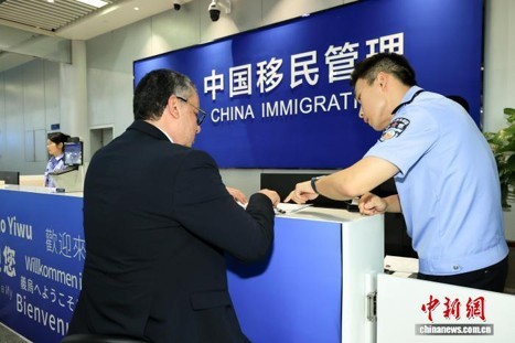 An immigration staff member assists a foreign traveler with visa applications at Yiwu Airport on July 16, 2026. (Photo/Wang Jianfei)