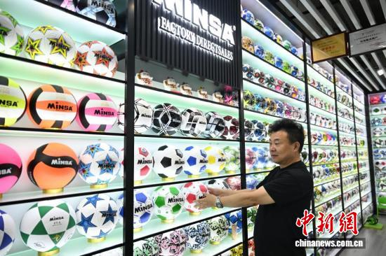 A merchant in Yiwu displays various FIFA World Cup 2026 commemorative footballs, June 6, 2026. (Photo: China News Service/Wang Gang)