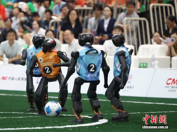 The orange robot of “Tiangong II” (Beijing Miyun No. 2 High School) and the blue robot of “Jinggong” (Experimental School Affiliated to BIT) compete in the humanoid football final at Tsinghua University High School on July 22, 2026. (Photo: China News Service / Jiang Qiming)