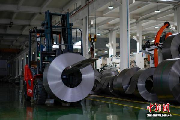 Workers transport steel coils for the production of export-oriented steel furniture. (Photo: China News Service / Li Chaoqing)