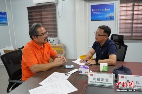 Li Huansong (left), leader of the 21st Chinese medical team to Guyana, provides medical consultation at the event, August 5, 2026. (Photo: China News Service/ Li Yanyu)