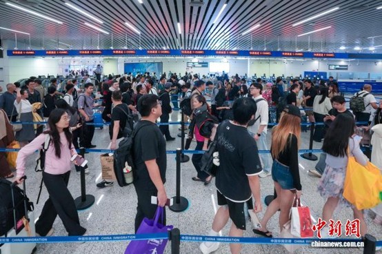 Travelers queue up for clearance via e-gates in the arrivals hall of Terminal 2, Guangzhou Baiyun International Airport. (Photo: China News Service/ Li Fengjun)
