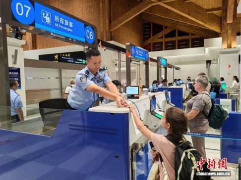 An immigration officer at the Sanya Phoenix immigration inspection station processes a passenger’s clearance, Oct. 5, 2026. (Photo: China News Service/Zhang Song)