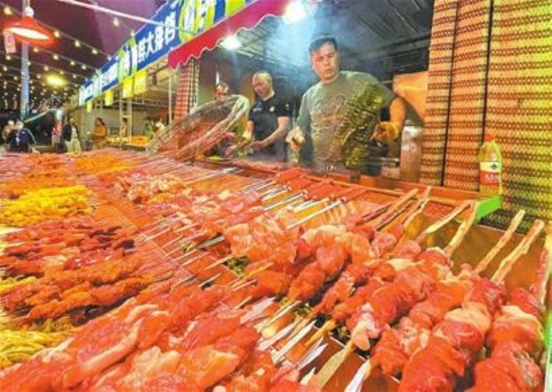 4月26日，在振安街創(chuàng)業(yè)廣場夜市，烤肉師傅為顧客準(zhǔn)備烤肉。（本報(bào)實(shí)習(xí)記者米熱扎提攝）