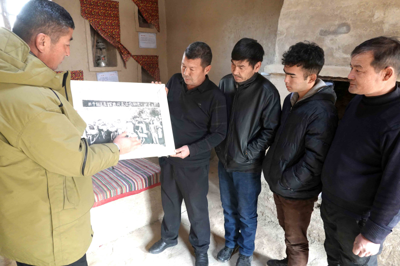 12月27日，吐玉洪·吾吉合买提（左）正在向村民讲述老照片背后的故事。邹焰忠 摄