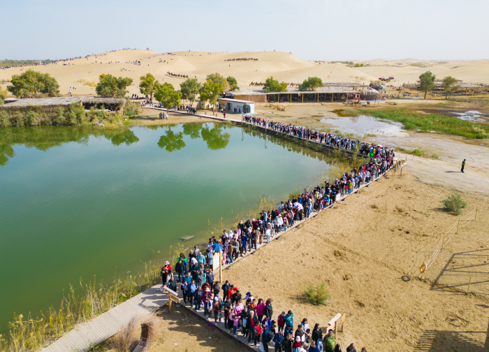 10月4日，尉犁縣羅布人村寨旅游景區(qū)游客在有序乘坐區(qū)間車。