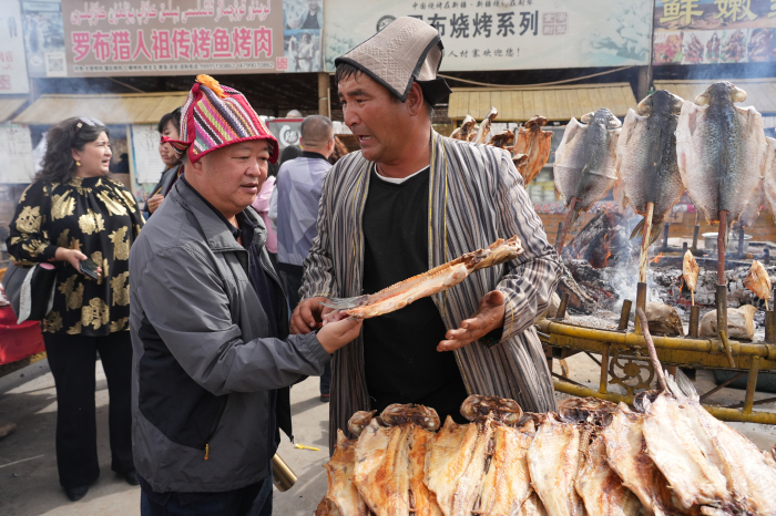 10月4日，尉犁縣羅布人村寨旅游景區(qū)阿不旦廣場，游客購買羅布烤魚。