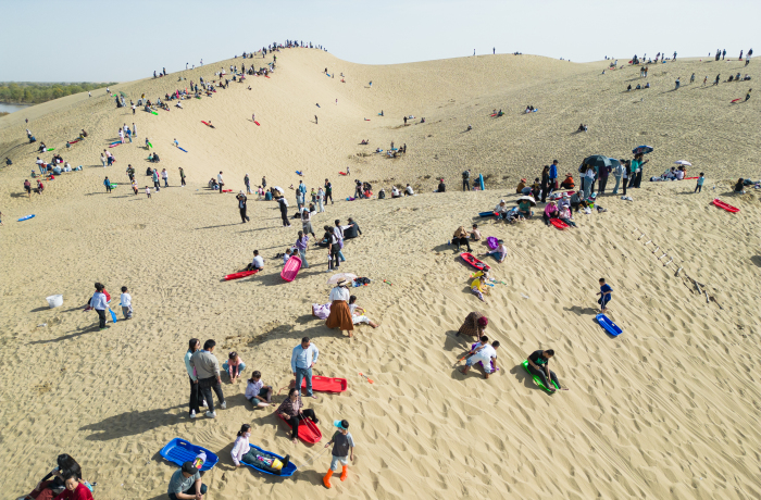 10月4日，尉犁縣羅布人村寨旅游景區(qū)游客在東沙山體驗滑沙等項目。