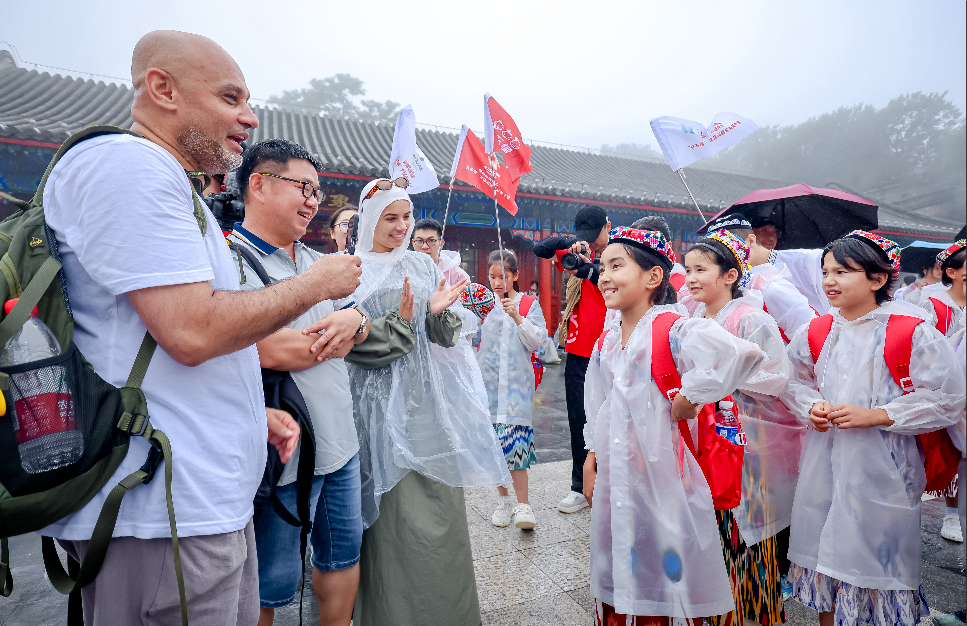 “红石榴”夏令营的孩子们与外国游客交流。张利民 摄