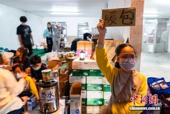 11月27日晚，青少年参与为火灾受影响市民提供热水、暖包等物资帮助。a target='_blank' href='/'中新社/a记者 侯宇 摄