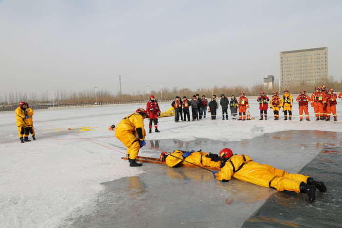 图为演练现场，消防救援人员利用单杠梯救援技术营救落水群众。