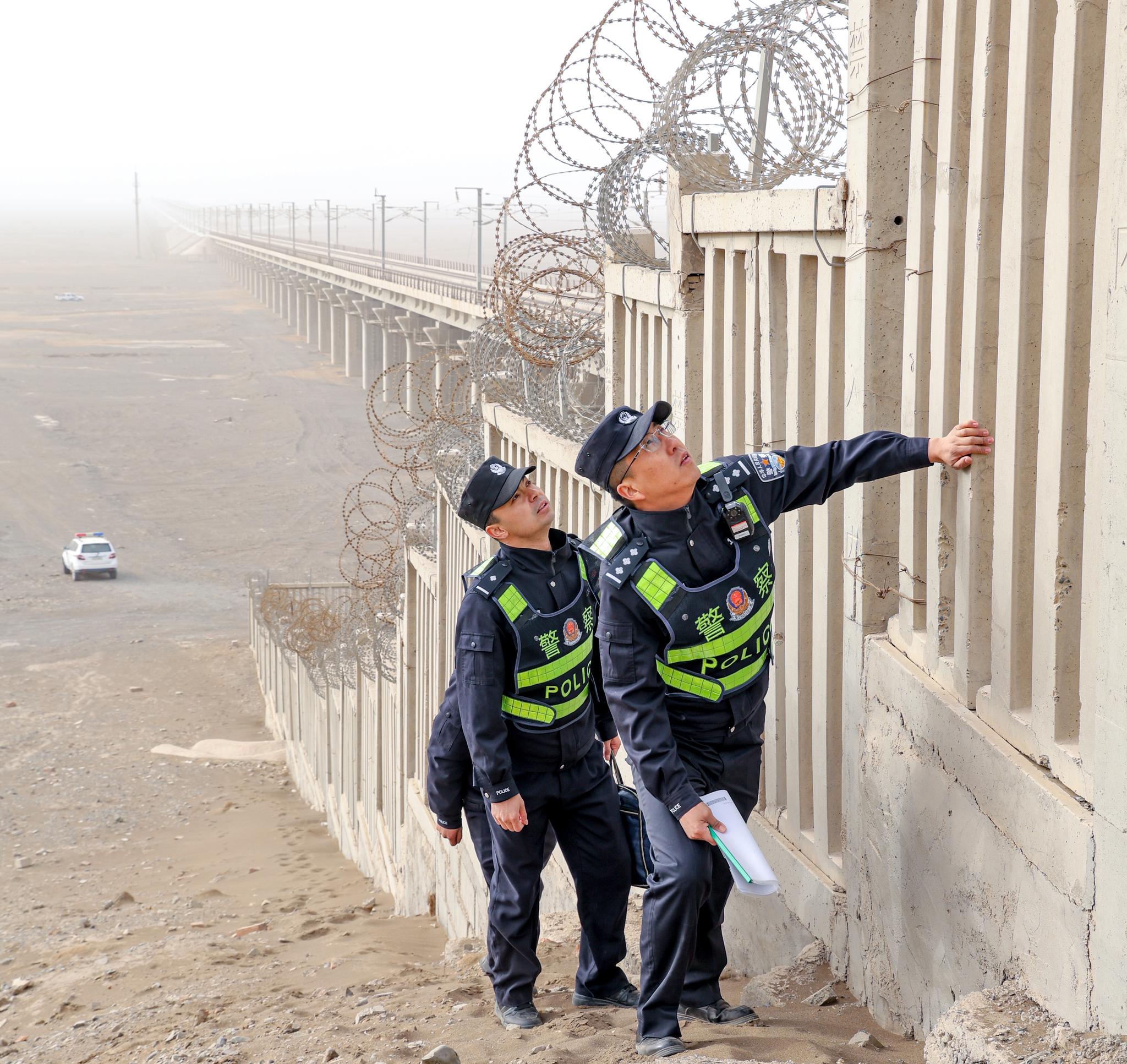 民警在沙尘天气下对兰新客专线物防设施开展安全巡查。