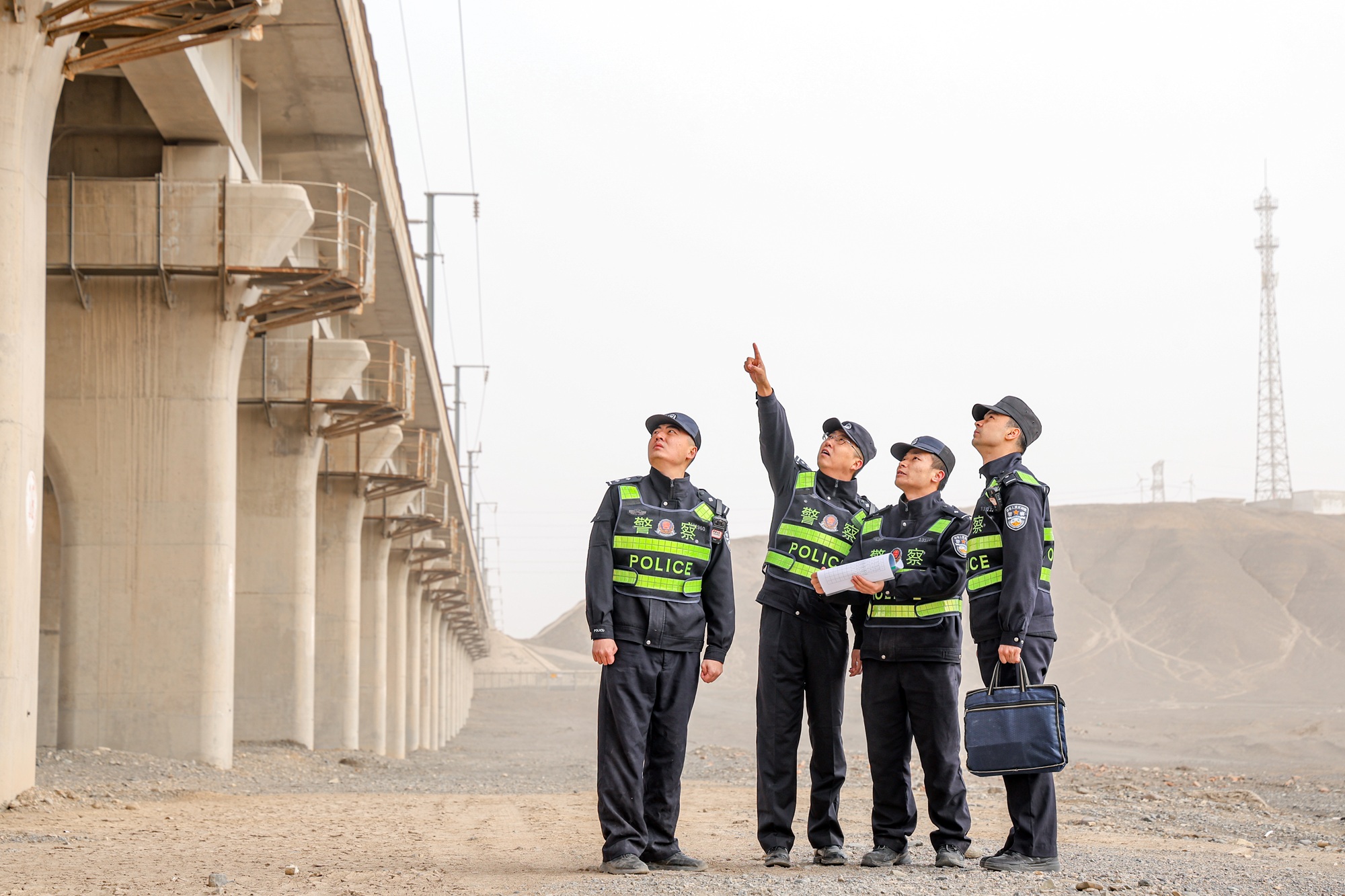 民警在沙尘天气下对兰新客专线物防设施开展安全巡查。