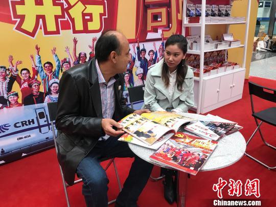 迪力夏提·阿不力孜向帕丽达·达吾提介绍“民族团结一家亲号”特快旅客列车一年来的情况。 迪娜 摄