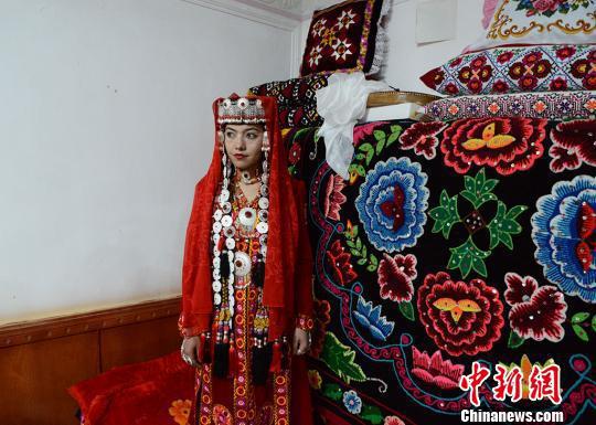 盛装打扮的新娘祖木莱提在她的闺房中等待接亲队伍的到来。屋外是庆祝婚礼载歌载舞的人群。 勉征 摄
