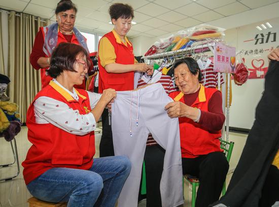 在呼图壁县“阿同汗”社区的爱心超市里,王桂珍(右一)与“阿同汗”志愿服务队的队员们一起整理衣服。 在呼图壁县“阿同汗”社区的爱心超市里,王桂珍(右一)与“阿同汗”志愿服务队的队员们一起整理衣服。
