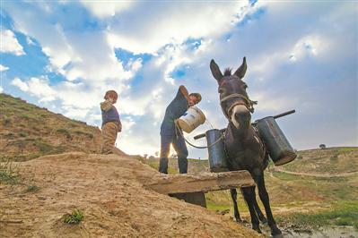 <p>　　2016年10月海原县郑旗乡南山村村民用驴驮水。如今，这种方式已成为历史。　马德　摄</p>