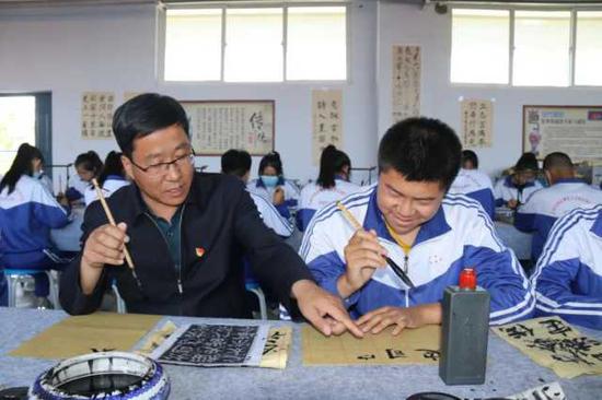 李新华（左一）指导学生练习书法。