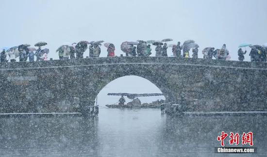 众多游人撑伞在西湖断桥上赏雪。王刚 摄