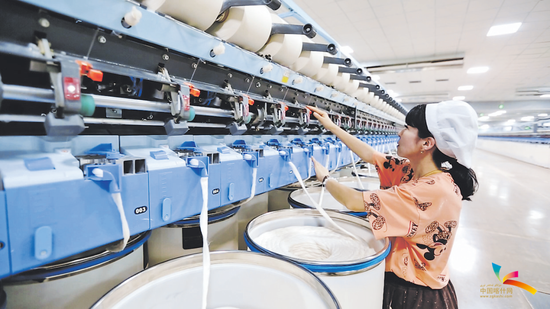 巴楚县工业园区新疆华凯医疗用品有限公司纺纱车间工人在纺织机前忙碌。