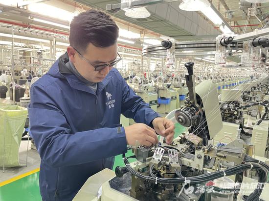 5月2日，在新疆唐锦纺织有限公司的生产车间，工作人员正在对全自动织袜机进行维修。图片由受访企业提供