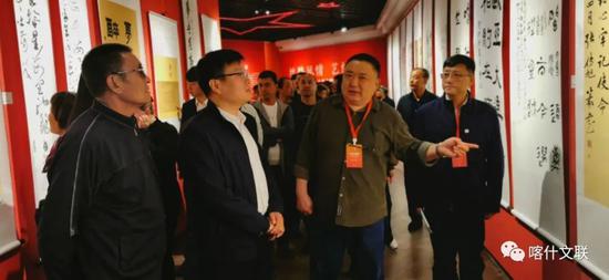 “丝路风情 艺结同心——山东·喀什美术书法摄影民艺作品联展”活动中，山东省文联艺术家向大家介绍书法作品。供图：阿布都艾则孜