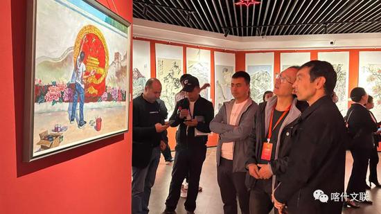 “丝路风情 艺结同心——山东·喀什美术书法摄影民艺作品联展”活动中，鲁喀两地艺术家共同观看油画。供图：阿漫提传媒