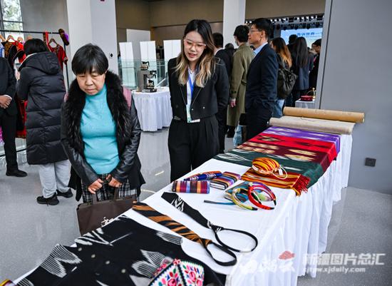 11月16日，参会者在分享会现场参观新疆特色手工制品。